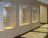 A wall with three glass cases on it.